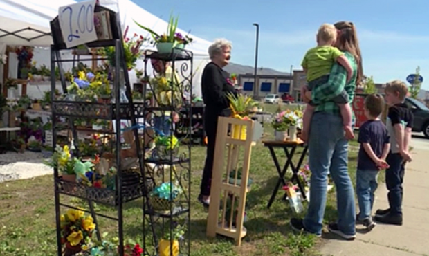 Kathy Giles talks to a family at her roadside artificial flower stand. (KSL TV)...