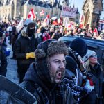 OTTAWA, ON - JANUARY 30: A man carrying a hockey stick reacts to a speaker during a rally where thousands gathered to protest COVID-19 vaccine mandates on January 30, 2022 in Ottawa, Canada. Thousands turned up over the weekend to rally in support of truckers using their vehicles to block access to Parliament Hill, most of the downtown area Ottawa, and the Alberta border in hopes of pressuring the government to roll back COVID-19 public health regulations. (Photo by Alex Kent/Getty Images)