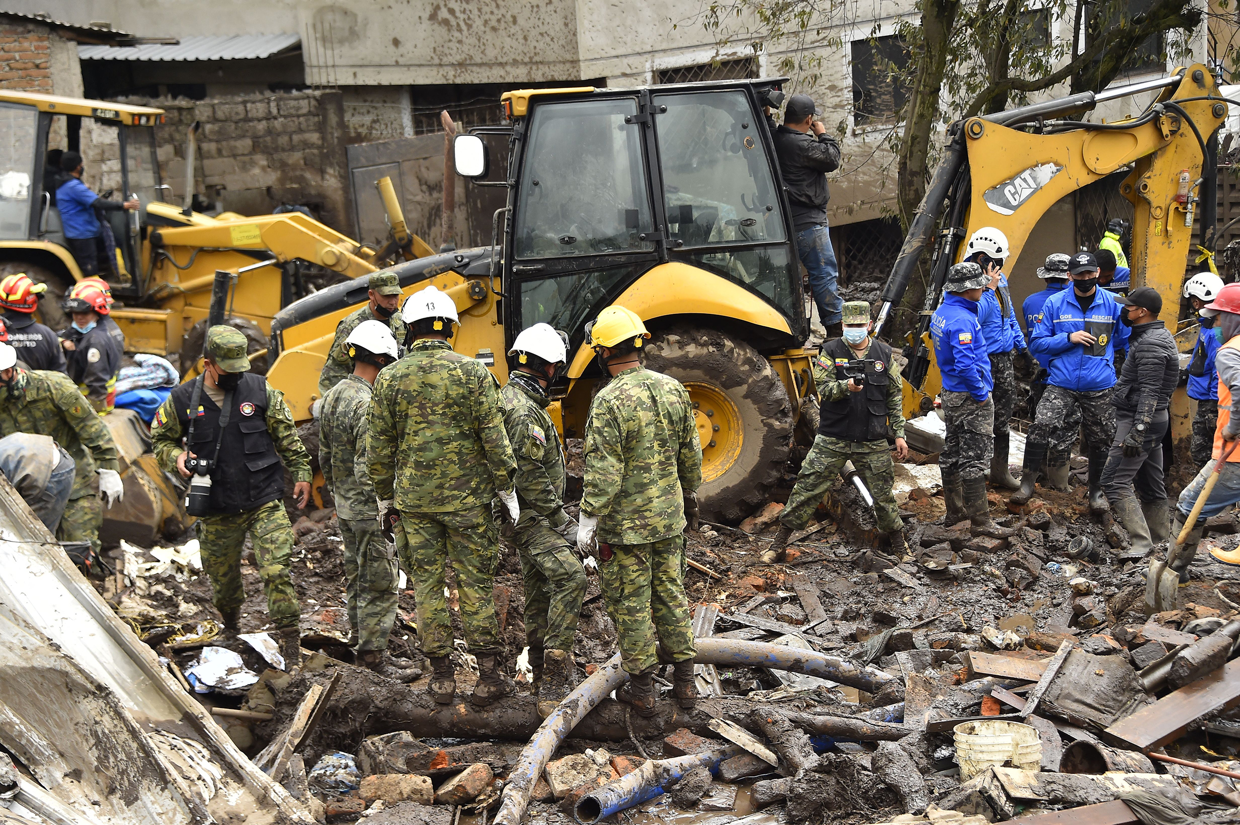 Firefighters and army members are seen next to machinery amid mud during the search for victims in ...