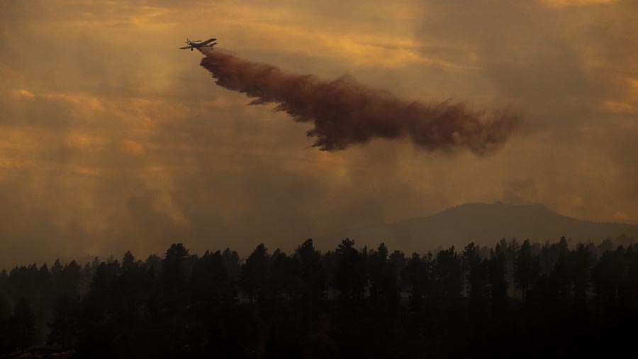 BOULDER, CO - MARCH 26: An air tanker drops slurry on the NCAR Fire on March 26, 2022 in Boulder, C...
