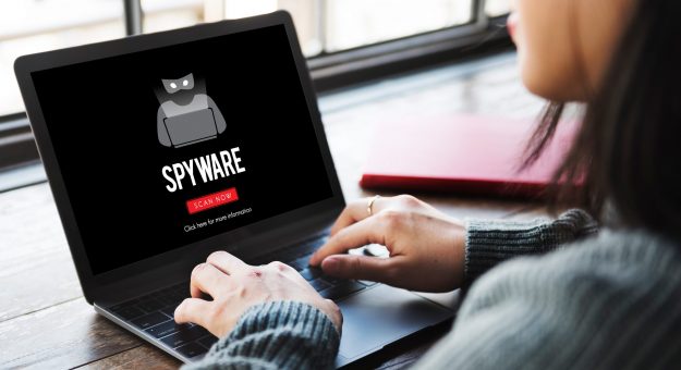 woman at laptop with spyware shown on screen
