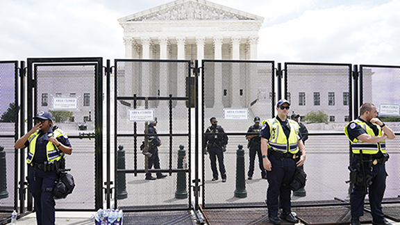 Authorities stand guard by a fence outside the Supreme Court following Supreme Court's decision to ...