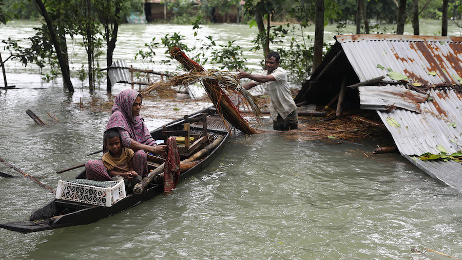 A family collects their goods  before leaving their submerged home after flash floods at Goainghat ...