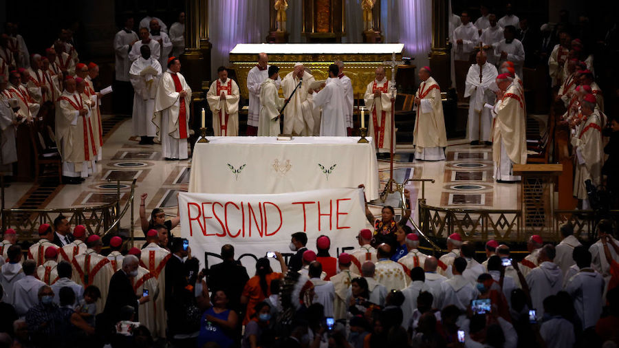 Indigenous protesters hold up a sign in front of Pope Francis as he celebrates mass at the National...
