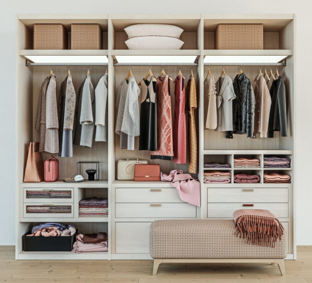 modern wooden wardrobe with clothes hanging on rail in walk in closet