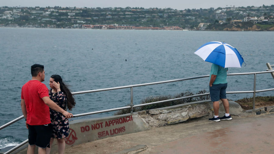 Visitors overlook the Pacific Ocean as rain and wind batter the coast due to Hurricane Kay on Septe...