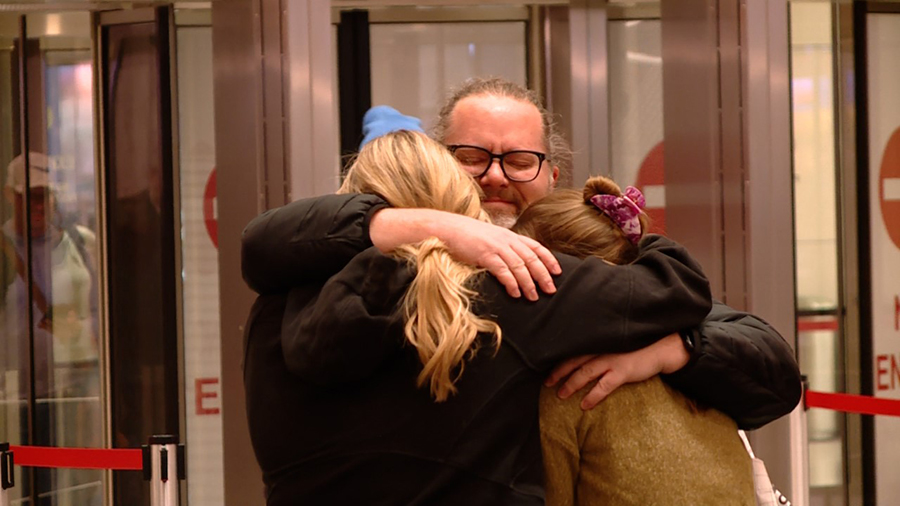 Two girls hugging their father at the airport...