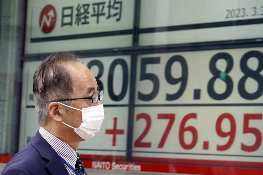 A person walks in front of an electronic stock board showing Japan's Nikkei 225 index at a securiti...
