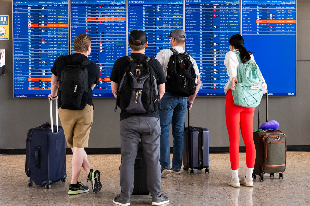 WASHINGTON, DC - JULY 19: Passengers look at a  flight information board showing multiple delays an...