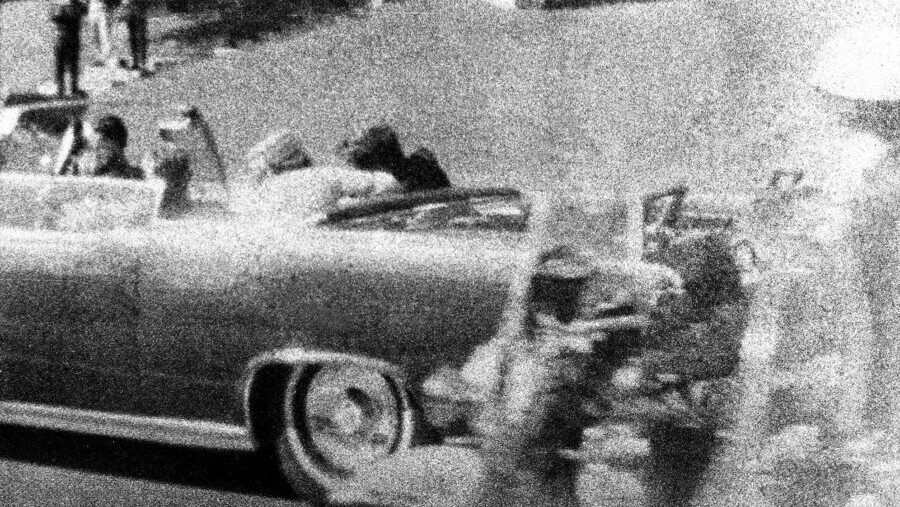 President John F. Kennedy slumps against his wife as the bullet from an assassin strikes him in the...