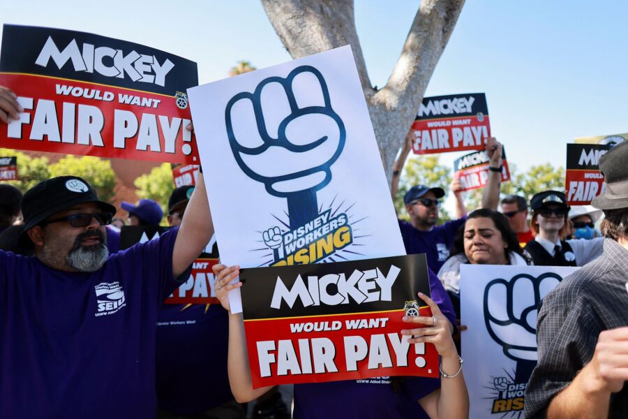 Workers gather with signs as the Teamsters union and Disney cast members demand fair wages at a ral...